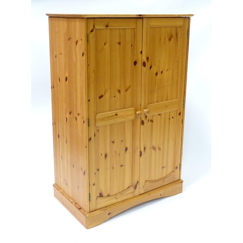 555 - A modern pine cupboard with two panelled doors with turned knob handles and having a fitted interior... 