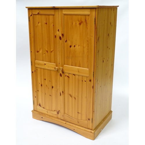 555 - A modern pine cupboard with two panelled doors with turned knob handles and having a fitted interior... 