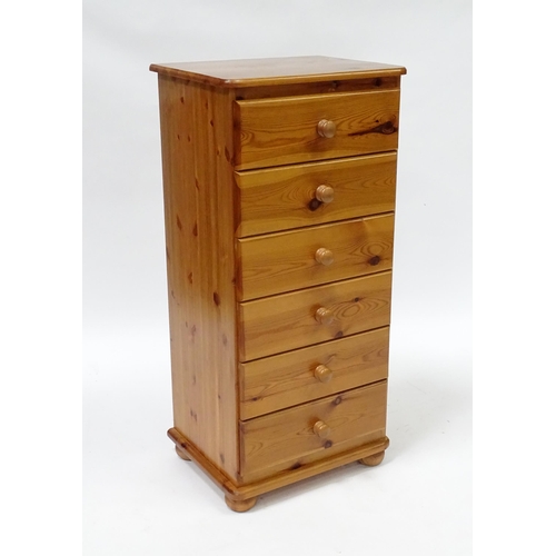 559 - A pine chest of six short drawers with turned wooden handles, raised on four squat bun feet. 2