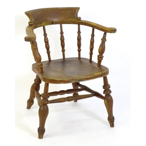 87 - An early 20thC smokers bow armchair, with scrolled and a shaped seat raised on turned tapering legs ... 