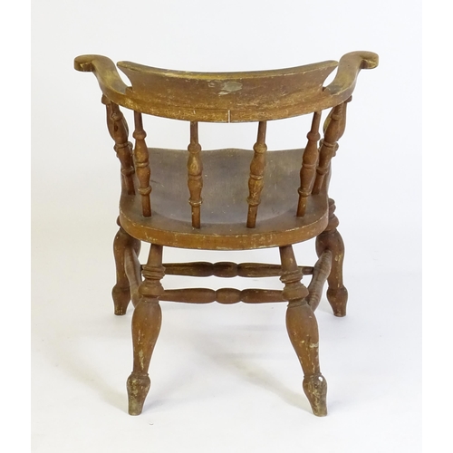 87 - An early 20thC smokers bow armchair, with scrolled and a shaped seat raised on turned tapering legs ... 