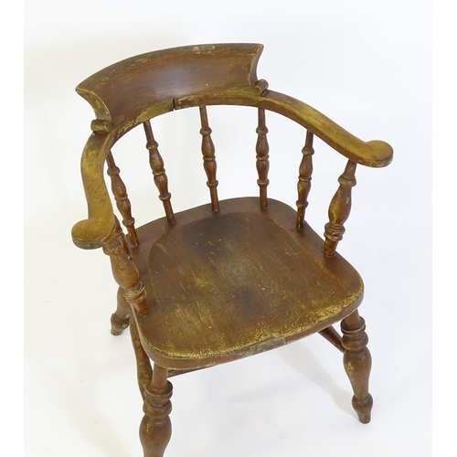 87 - An early 20thC smokers bow armchair, with scrolled and a shaped seat raised on turned tapering legs ... 