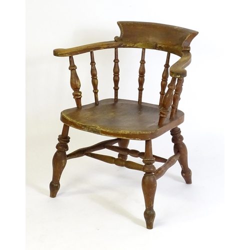 87 - An early 20thC smokers bow armchair, with scrolled and a shaped seat raised on turned tapering legs ... 