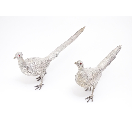 592 - A large pair of silver pheasants modelled as a cock and a hen pheasant with red glass eyes. Hallmark... 