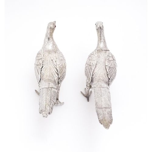 592 - A large pair of silver pheasants modelled as a cock and a hen pheasant with red glass eyes. Hallmark... 