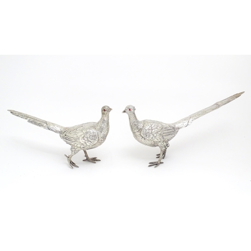 592 - A large pair of silver pheasants modelled as a cock and a hen pheasant with red glass eyes. Hallmark... 