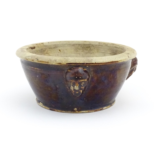 62 - A stoneware bowl with a treacle glaze and three relief masks to side. Approx. 3