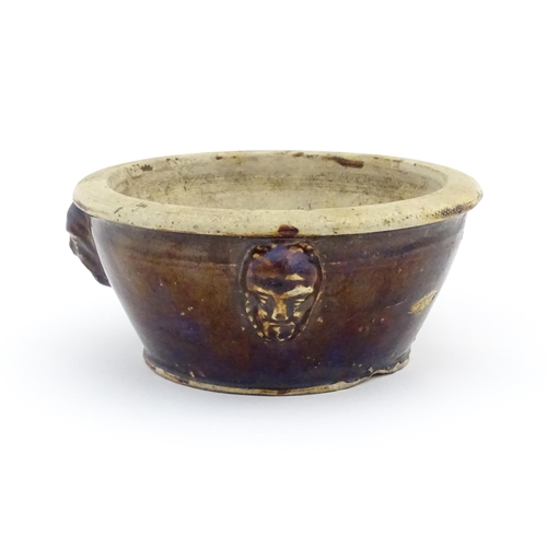 62 - A stoneware bowl with a treacle glaze and three relief masks to side. Approx. 3