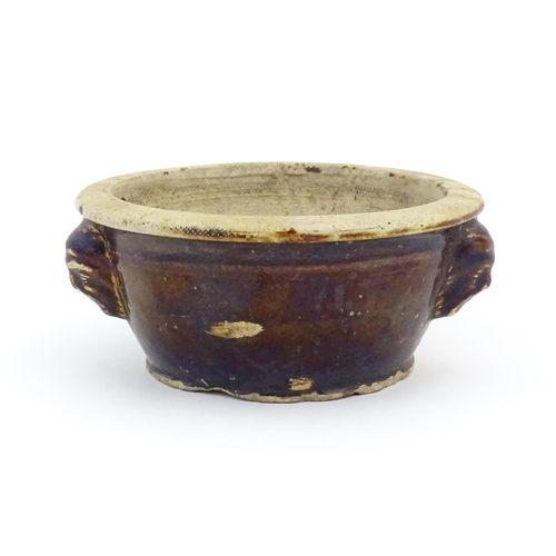 62 - A stoneware bowl with a treacle glaze and three relief masks to side. Approx. 3