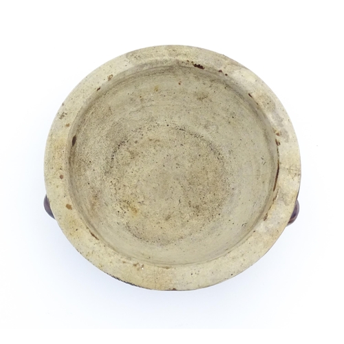 62 - A stoneware bowl with a treacle glaze and three relief masks to side. Approx. 3