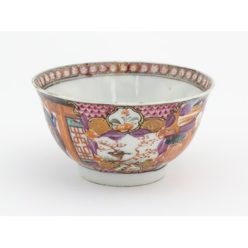 65 - A Miles Mason style tea bowl and saucer in the pattern Boy At Door, depicting Oriental figures in a ... 