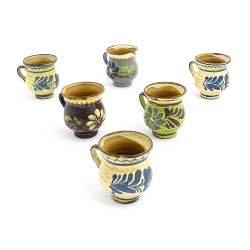 86 - Five French earthenware mugs and a jug with slip glaze and floral / foliate decoration. Approx. 4