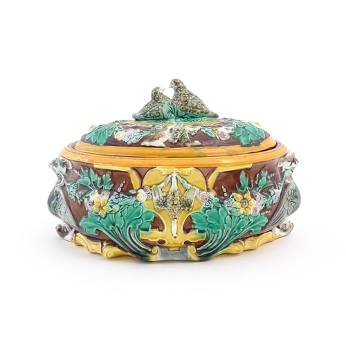 136 - A Victorian majolica game pie dish and cover, the body decorated in relief with birds, flowers and f... 