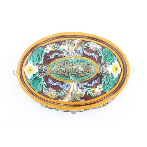 136 - A Victorian majolica game pie dish and cover, the body decorated in relief with birds, flowers and f... 