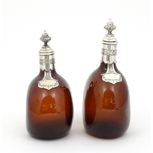 235 - Two 19thC amber glass flasks / decanters with silver plate mounts. Largest approx 9