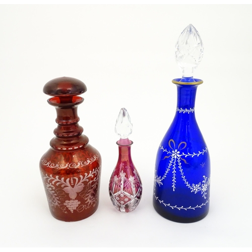 250 - Three assorted glass decanters to include ruby, blue and cranberry coloured examples. The largest ap... 