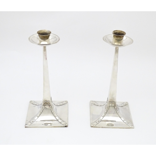 288 - A pair of Arts and Crafts silver candlesticks  of tapering square form, circular capitals and drip p... 