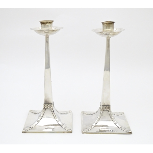 288 - A pair of Arts and Crafts silver candlesticks  of tapering square form, circular capitals and drip p... 