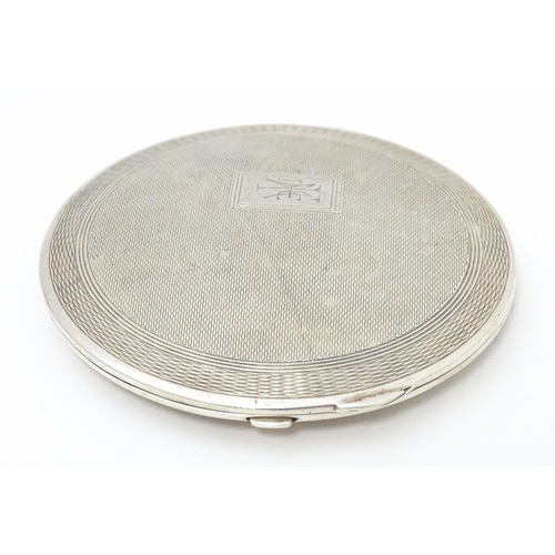 336 - An Art Deco silver powder compact with engraved decoration and lid opening to reveal mirror within. ... 