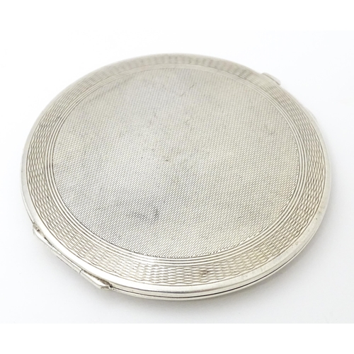 336 - An Art Deco silver powder compact with engraved decoration and lid opening to reveal mirror within. ... 