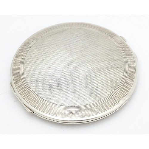 336 - An Art Deco silver powder compact with engraved decoration and lid opening to reveal mirror within. ... 