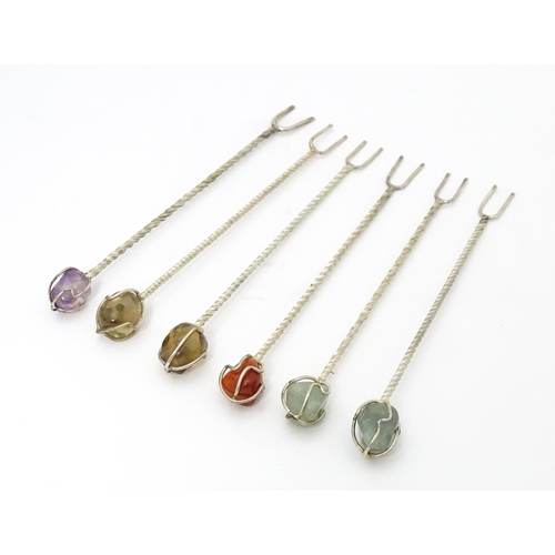 346 - Six white metal cocktail sticks / forks each surmounted with a polished hardstone. Approx. 4 1/2