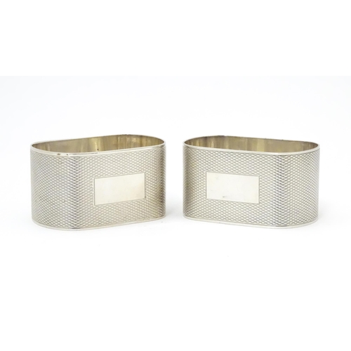 548 - A pair of silver napkin rings of ovoid form with engine turned decoration, hallmarked Birmingham 195... 