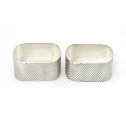 548 - A pair of silver napkin rings of ovoid form with engine turned decoration, hallmarked Birmingham 195... 