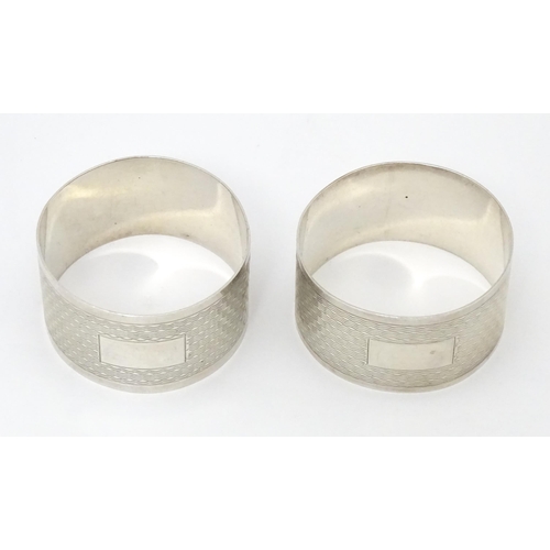 570 - A pair of silver napkin rings with engine turned decoration, hallmarked Birmingham 1957, maker Willi... 