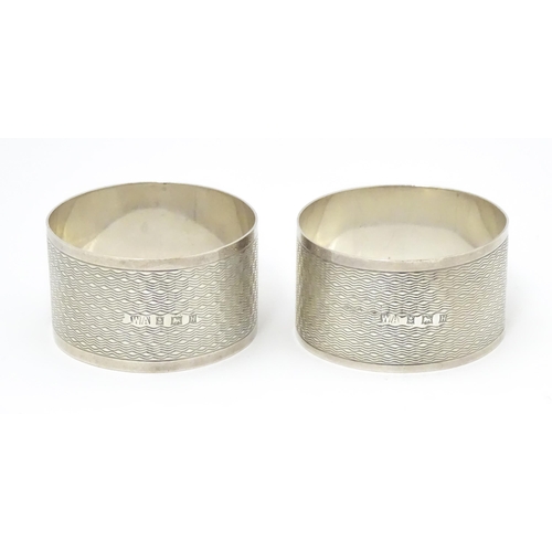 570 - A pair of silver napkin rings with engine turned decoration, hallmarked Birmingham 1957, maker Willi... 