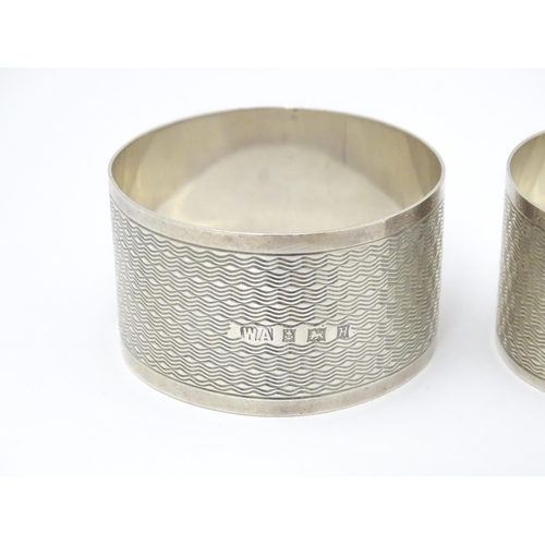 570 - A pair of silver napkin rings with engine turned decoration, hallmarked Birmingham 1957, maker Willi... 