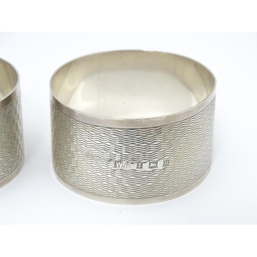 570 - A pair of silver napkin rings with engine turned decoration, hallmarked Birmingham 1957, maker Willi... 