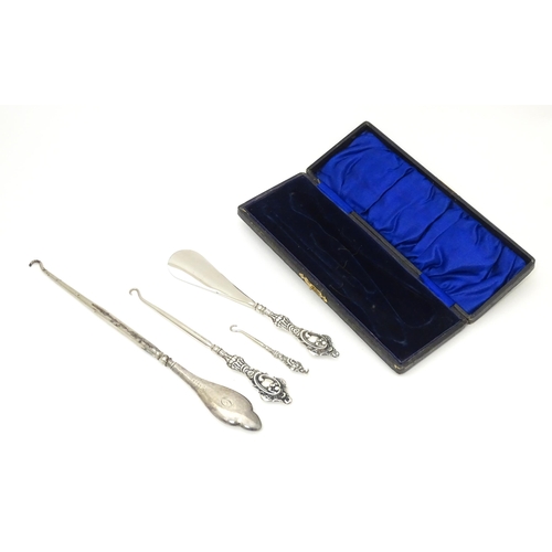 575 - A case containing a matched set of silver handled button hooks and shoe horn, larger button hook, ha... 