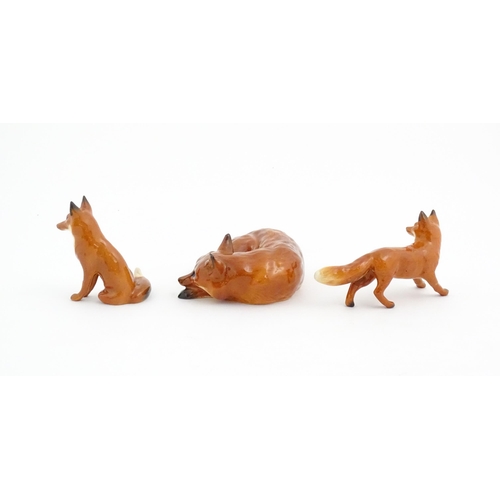 126 - Three Beswick models of foxes, comprising a seated fox, no. 1728, a standing fox, no. 1440, and a cu... 