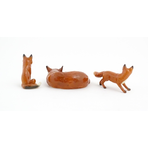 126 - Three Beswick models of foxes, comprising a seated fox, no. 1728, a standing fox, no. 1440, and a cu... 