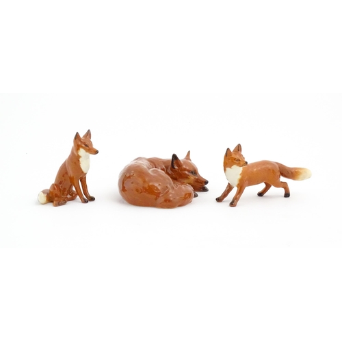 126 - Three Beswick models of foxes, comprising a seated fox, no. 1728, a standing fox, no. 1440, and a cu... 