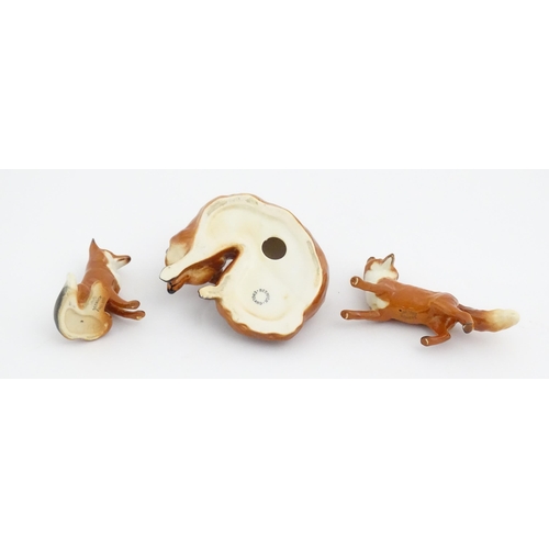 126 - Three Beswick models of foxes, comprising a seated fox, no. 1728, a standing fox, no. 1440, and a cu... 