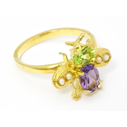 641 - A silver gilt ring with bee / winged insect decoration set with amethyst, pearl and peridot. Ring si... 