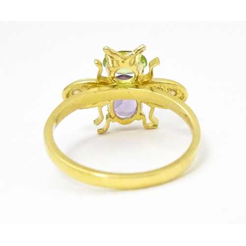 641 - A silver gilt ring with bee / winged insect decoration set with amethyst, pearl and peridot. Ring si... 