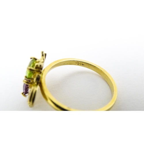 641 - A silver gilt ring with bee / winged insect decoration set with amethyst, pearl and peridot. Ring si... 