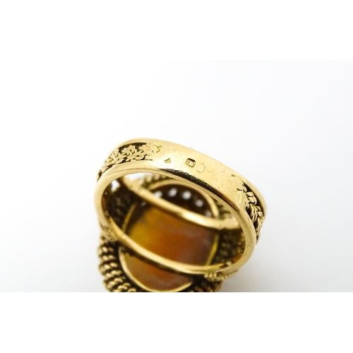 647 - A Continental gold ring set with central shell carved cameo with a filigree mount. Ring size approx.... 