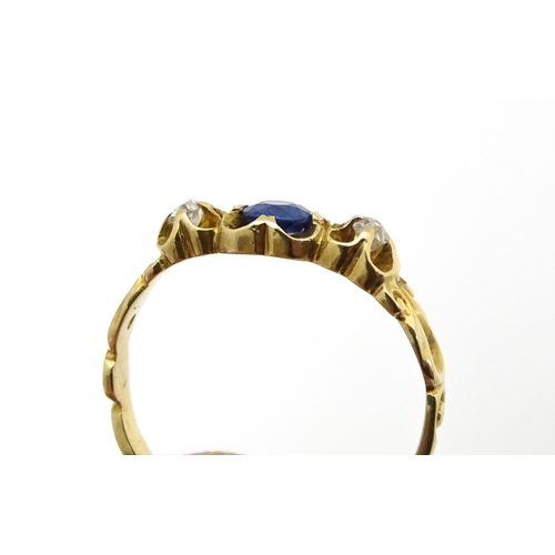 650 - A yellow metal ring set with central sapphire flanked by diamonds. Ring size approx. J