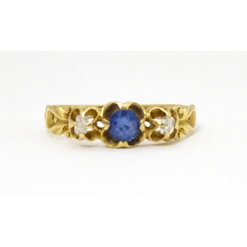 650 - A yellow metal ring set with central sapphire flanked by diamonds. Ring size approx. J