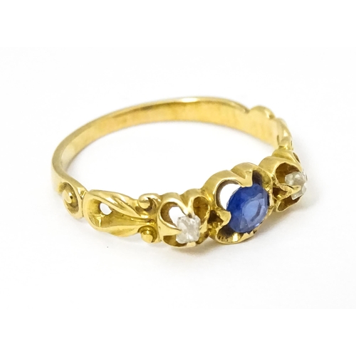 650 - A yellow metal ring set with central sapphire flanked by diamonds. Ring size approx. J