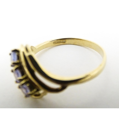 653 - A 9ct gold ring set with three pale lilac iolite. Ring size approx.