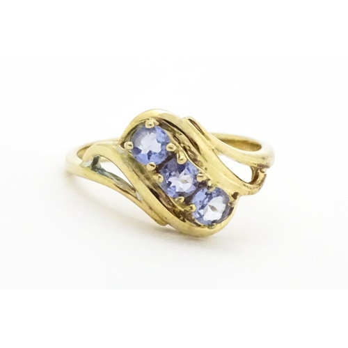 653 - A 9ct gold ring set with three pale lilac iolite. Ring size approx.