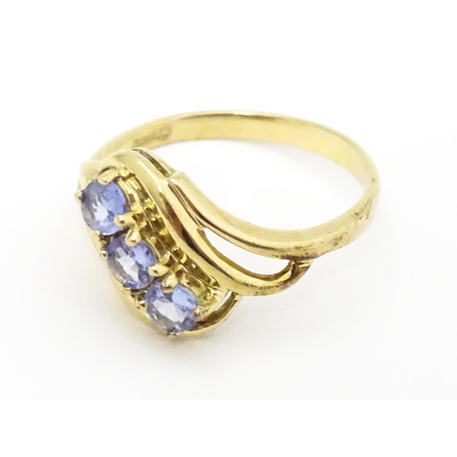 653 - A 9ct gold ring set with three pale lilac iolite. Ring size approx.