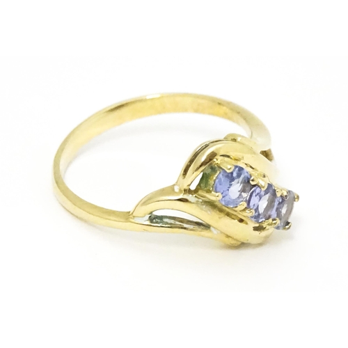 653 - A 9ct gold ring set with three pale lilac iolite. Ring size approx.