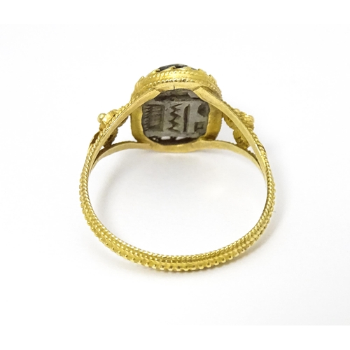 656 - Egyptian Revival Jewellery : A Continental yellow metal ring with carved hardstone scarab beetle det... 