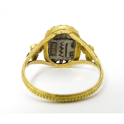 656 - Egyptian Revival Jewellery : A Continental yellow metal ring with carved hardstone scarab beetle det... 